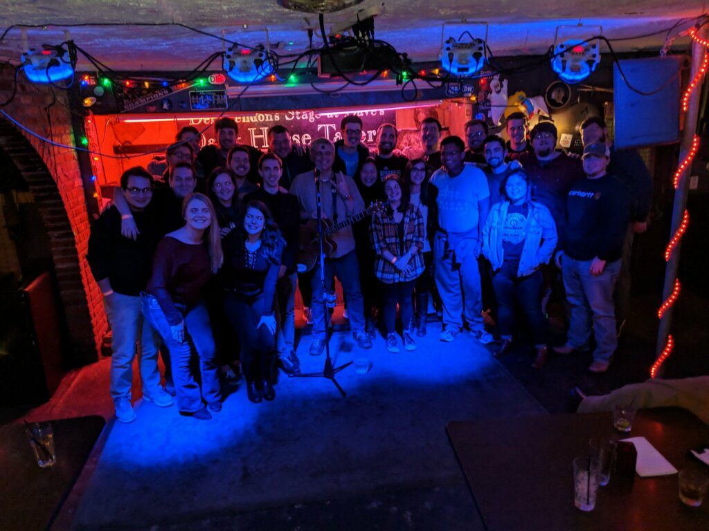 Spencer Callicott and a packed crowd at a live music venue lit up in blue stage lights